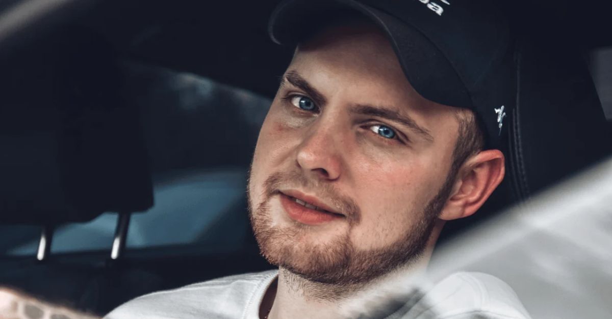 Close-up of a smiling, bearded man with blue eyes sitting in a car, creating a relaxed atmosphere.