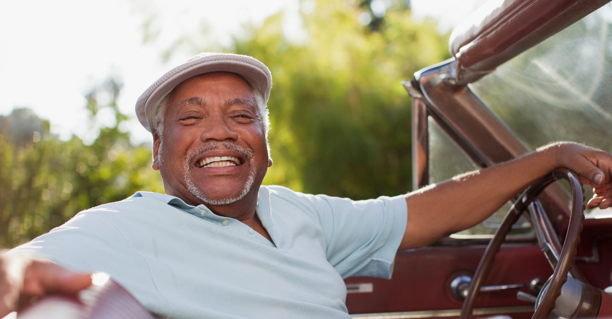 Smiling older man driving convertible