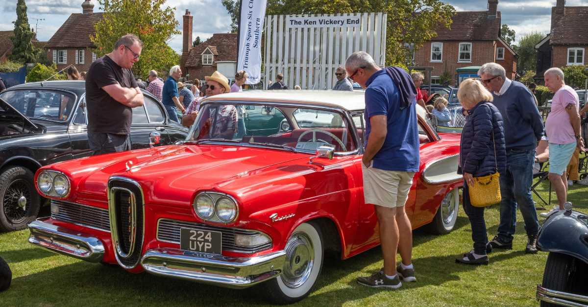 People stop to look at a bright red 1958 Ford Edsel car