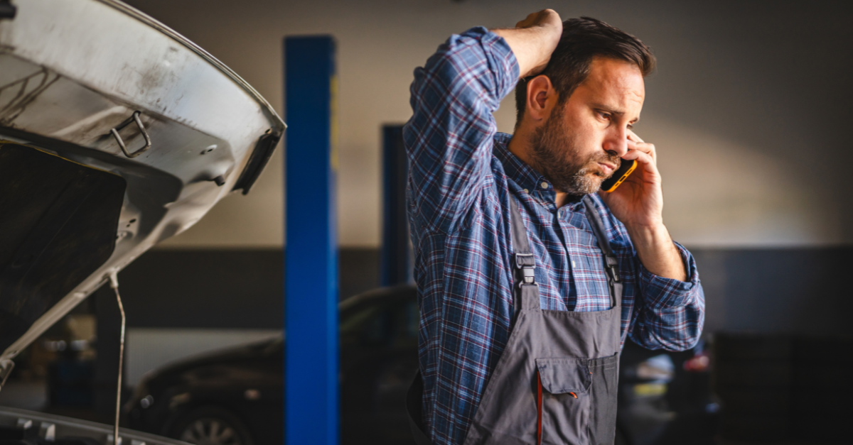 A car mechanic in a plaid shirt and overalls