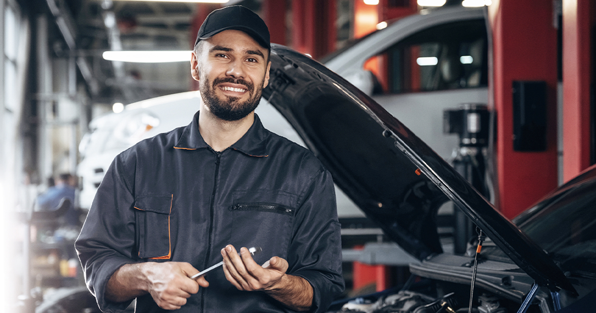 Mechanic standing in garage holding a tool