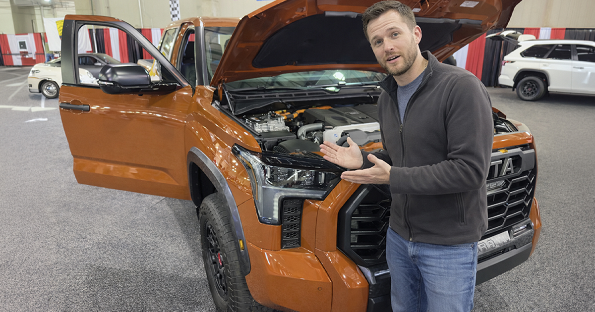 Orange 2023 Toyota Tundra full size pick up truck with open doors and hood displayed at an auto show.