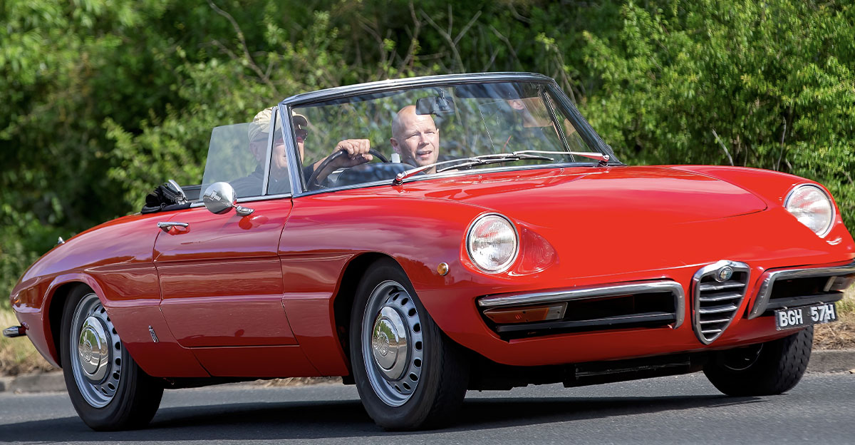 1970 red Alfa Romeo Spider classic car driving on a British road