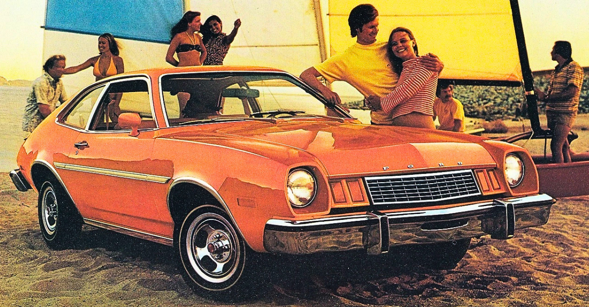 A vintage 1970s print advertisement featuring a bright orange 1977 Ford Pinto parked on a sandy beach.