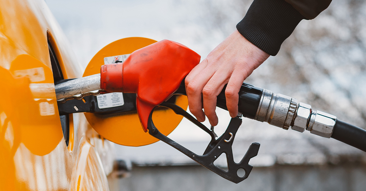 Hand holding a gas pump, filling his car's tank.