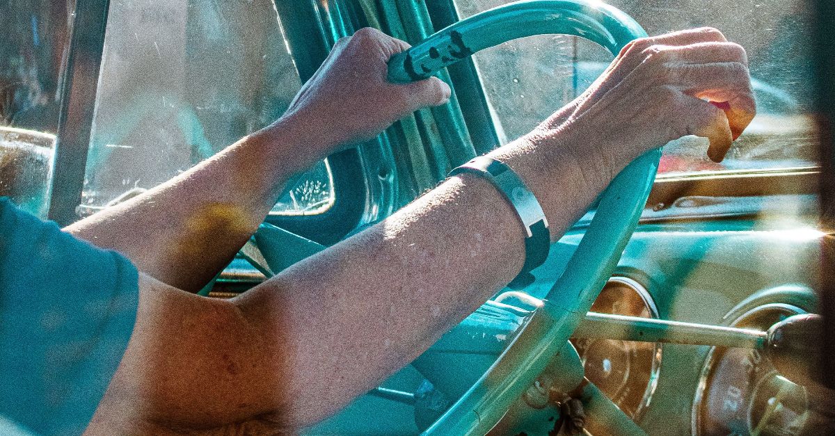 A driver navigates an old vintage car, hands on the steering wheel, sunlight streaming through the window.